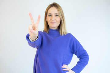 Portrait of a smiling happy woman showing victory sign and looking at camera isolated on the white background