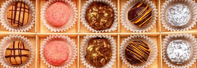 Set of chocolate truffle made of dark and milk chocolate with orange glaze, strawberries (cranberries, raspberries), coconut and powdered sugar. Sweet gift of candy in a craft box. banner