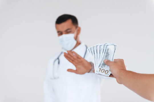 Medic Won't Take Bribe. Young Handsome Man Standing Indoors Against White Background