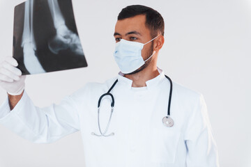 Medic with x-ray. Young handsome man standing indoors against white background