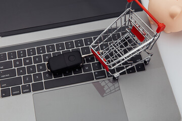 Car key and shopping trolley above laptop keyboard.