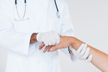 Medic works with patient's hand. Close up particle view of young man that standing indoors against white background