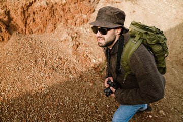 Focused handsome photographer walking with digital camera