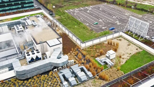 Roofs with greenery and communications of modern office buildings, parking on the background. View from the drone at cloudy weather in Bucharest, Romania