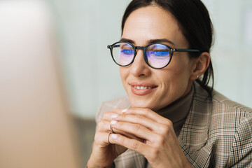Smiling charming woman in eyeglasses working with computer