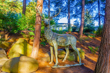 Bronze sculpture of a deer in the park in summer.