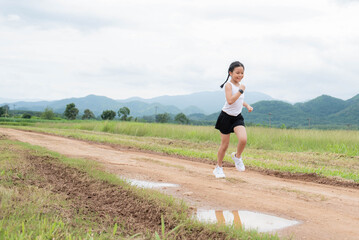 Happy Funny little asian girl fitness woman running at morning tropical forest trail. Athletic young child running in the nature. Healthy lifestyle.