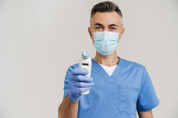 Medical doctor in face mask and gloves posing with infrared thermometer