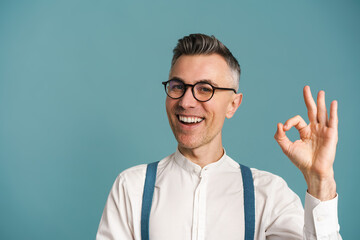 Excited grey-haired man in eyeglasses showing ok sign