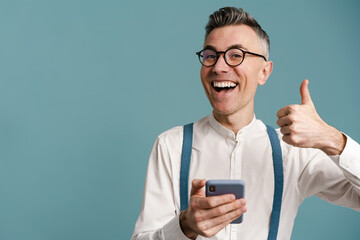 Happy grey-haired man showing thumb up and using cellphone