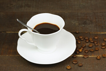 White Cup of black coffee and coffee beans on wooden background. 