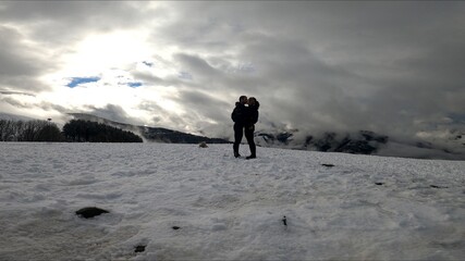 young couple kissing in a snowed mountain