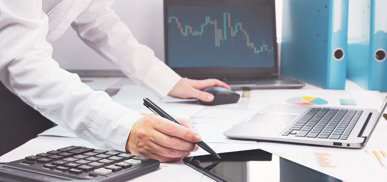 Stock Exchange Trade And Forex Financial Concept. Laptop With Graphs On Desk With Copy Space. Hand With Calculator. Distant Learning Or Broker Working From Home Or Office, Online Business.