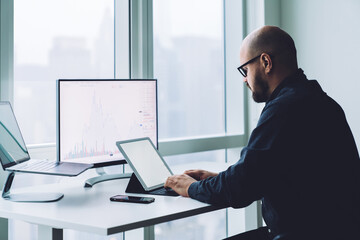 Focused broker typing on tablet keyboard while analyzing graphic
