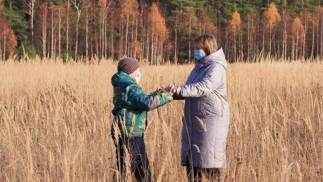 Mom and son dance on the tall grass, rejoice at freedom, have fun. Walk the autumn park. Rest, hiking in native nature. Healthy lifestyle concept. At sunset, in the evening, warm soft light
