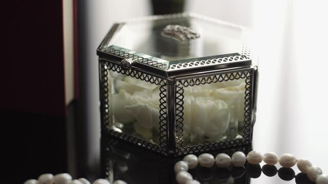 Wedding arrangement of a bouquet, women's shoes, rings and jewelry on a table with reflection. Box with wedding rings. Subject photography of the bride's set. Wedding decorations close-up.