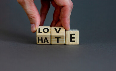 From hate to love symbol. Hand turns cubes and changes the word 'hate' to 'love'. Beautiful grey background, copy space. Valentines day and hate or love concept.