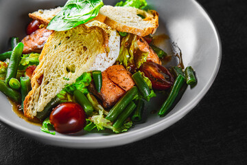 Green Bean Salad with Boiled Eggs, Salmon, Tomatoes and Arugula in a bowl on Dark grey black slate background