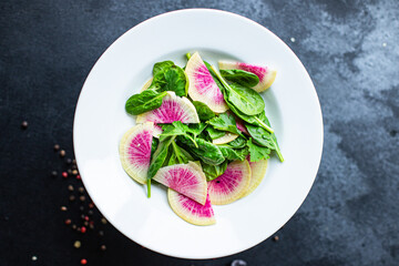 Watermelon radish fresh salad chinese daikon Slices pink fruit, green leaves spinach lettuce on the table healthy meal snack top view copy space food background keto or paleo diet
