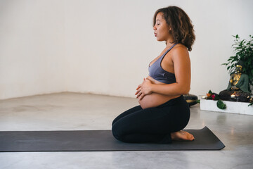 Young pregnant woman trains with yoga in the gym waiting for the birth of her baby - Concept of health and wellness - 405217159