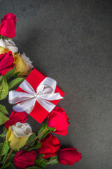 Valentine day greeting card with red rose flowers bouquet, wine and gift box on black table table. Top view with space for greetings