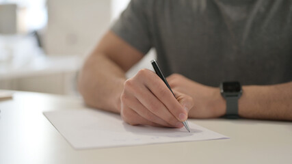 Hands of Young Man Writing on Paper, Close Up 