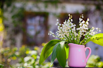 Lily of the Valley Bouquet in pink Vase vase in white polka dots, on the background of the house...