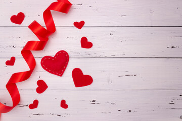 Red hearts and ribbon on a white wooden background. Top view, free space for text. Valentine's Day, love.