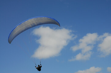 A paraglider flying along the clouds and blue skies of Africa