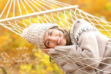 Happy woman with perfect smile resting on hammock in autumn