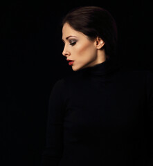 Naklejka premium Sexy woman with bright evening makeup, red lipstick brown brow posing isolated on dark black background. Closeup portrait in deep low key light shadows. Art.