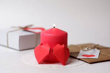 Couple of 3D red paper hearts, burning pink candle on white openwork paper napkin, gifts with labels, hearts closeup view selective focus. Love, Valentine's, women's day, relations, romantic concept