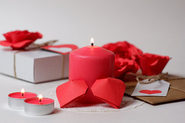 Couple of 3D red paper hearts, burning pink candles on white openwork paper napkin, gifts with labels, hearts, roses closeup view selective focus. Love, Valentine's, women's day, romantic concept