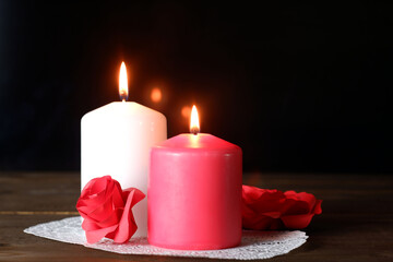 White and pink burning aromatic candles, roses, gift on white openwork paper napkin on wooden table, selective focus. Love, Valentine's, women's day, romantic, dating, rendezvous concept