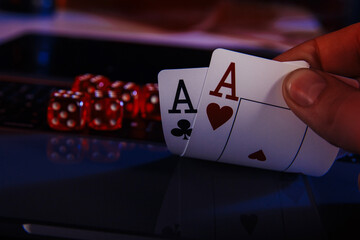 Dices and cards for poker in hand on laptop, online casino concept.