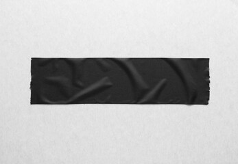 Black creased piece of matte cloth adheisive gaffer tape on grey cardboard background. Copy space...