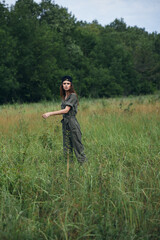 Woman In a green jumpsuit, a black cap is tall grass 