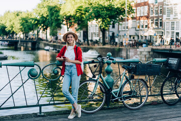 Positive woman standing near bicycles on bridge