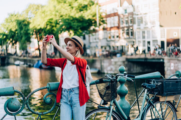 Plakat Cheerful female tourist taking photos on smartphone