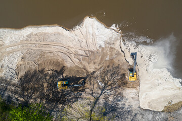 Yellow excavator digger working. Excavator digging sand, ground from water. Industrial aerial drone view.