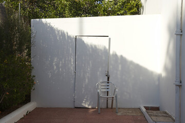 Empty chair in front of a white wall and door