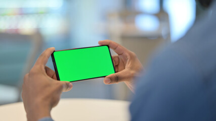 African Man Looking at Smartphone with Green Chroma Key Screen 