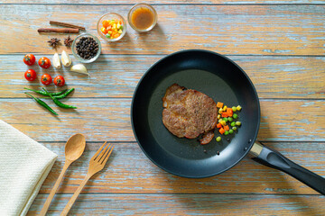 Grilled pork steak in frying pan over dark background, top view