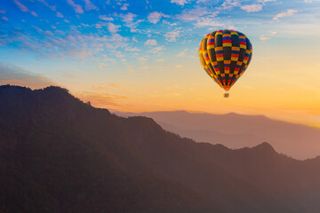 Colorful hot-air balloons flying over misty morning sunrise at Chiang Mai, Thailand.