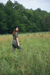 Naklejka na ściany i meble Woman in the meadow Walk in green jumpsuit black cap 