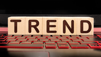 Trend word on wooden cubes on illuminated laptop keyboard. Popular and relevant topics.