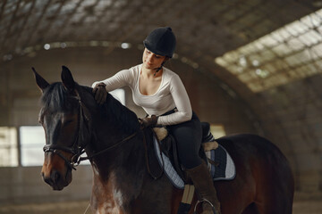 Cute girl with a horse. Lady in a white t-shirt. Woman in a summer ranch.