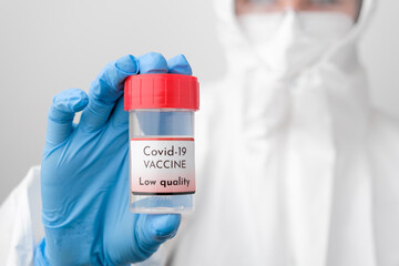 Covid 19 vaccine bottle in doctors hand. Doctor in protective suit, face mask, safety googles and rubber gloves demonstrate vaccine against coronavirus. 