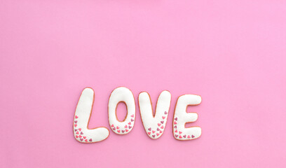 Cute gingerbread lettering LOVE with hearts decoration on pink