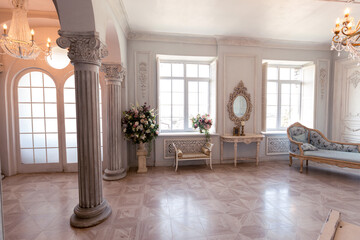 Luxurious light interior of the living room in the baroque style as in a royal castle with old stylish vintage furniture, columns, stucco on the walls